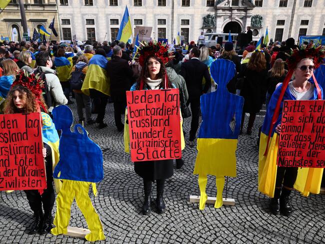 Munich (Germany), 17/02/2024.- Participants with flowers hold placards reading 'Every day Russia maims and kills civilians in Ukraine' (L), 'Every day Russia bombs hundreds of cities' (C) and 'Please imagine for a moment that your loved one could be next.' (R) in a Ukraine related protest in the course of the 60th Munich Security Conference (MSC) during a rally in Munich, Germany, 17 February 2024. More than 500 high-level international decision-makers meet at the 60th Munich Security Conference in Munich during their annual meeting from 16 to 18 February 2024 to discuss global security issues. (Protestas, Alemania, Rusia, Ucrania) EFE/EPA/ANNA SZILAGYI