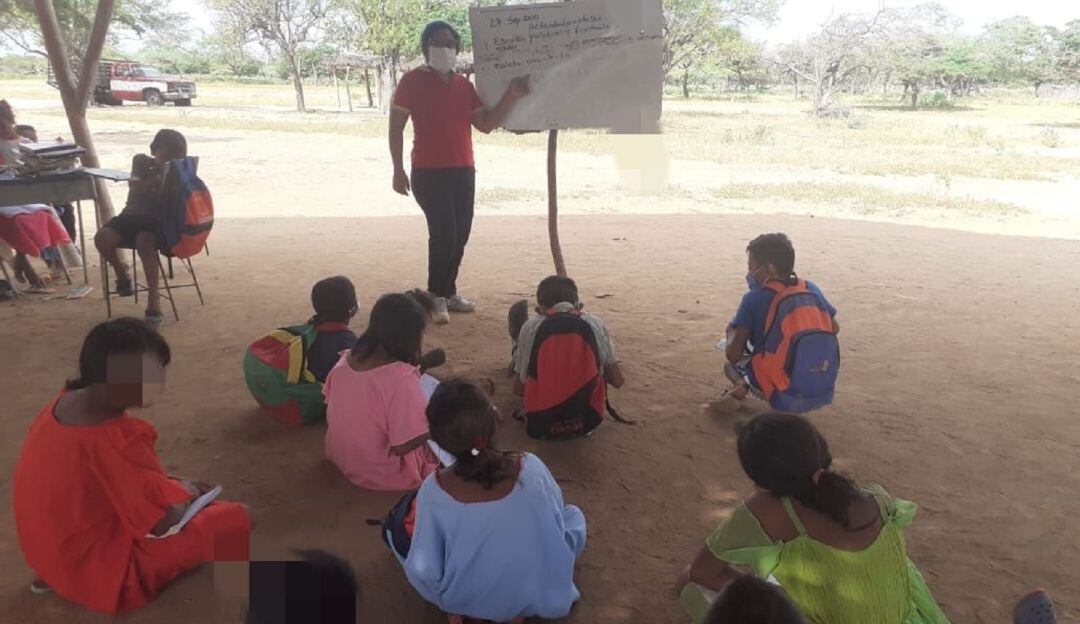 Niños recibiendo clases en el suelo
