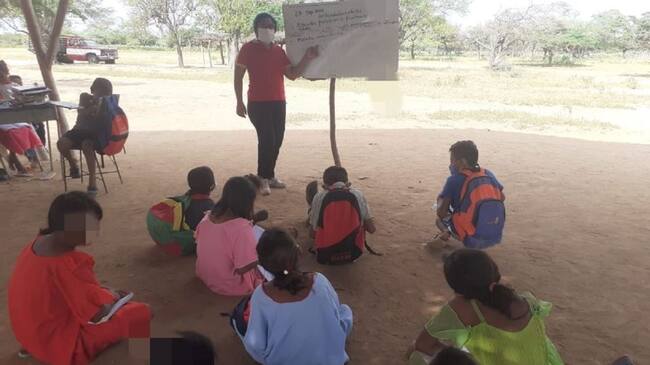 Niños recibiendo clases en el suelo