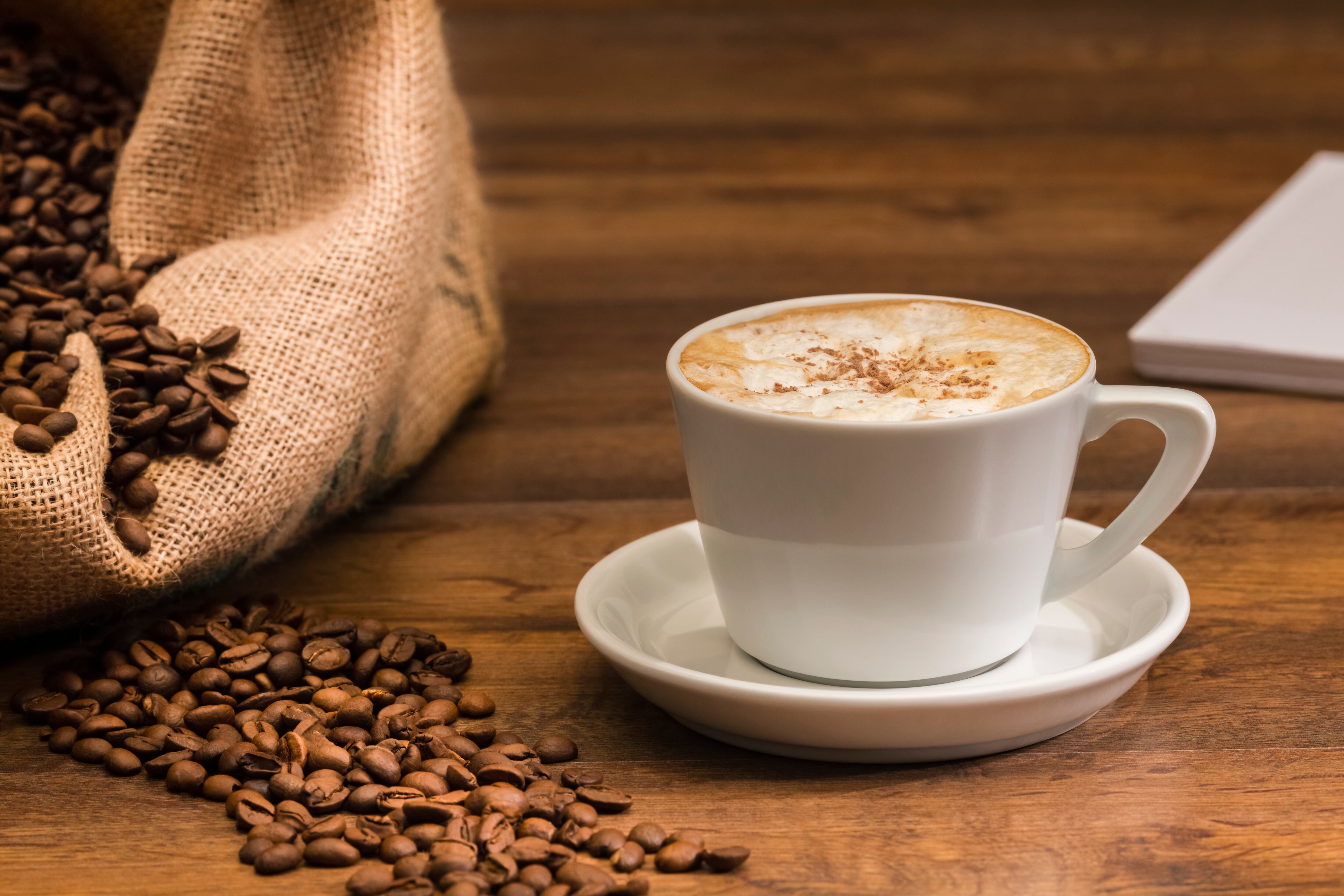 Close up of a freshly brewed cup of coffee with roasted coffee beans on an out of focus background. Selective focus. Coffee and leisure concept.