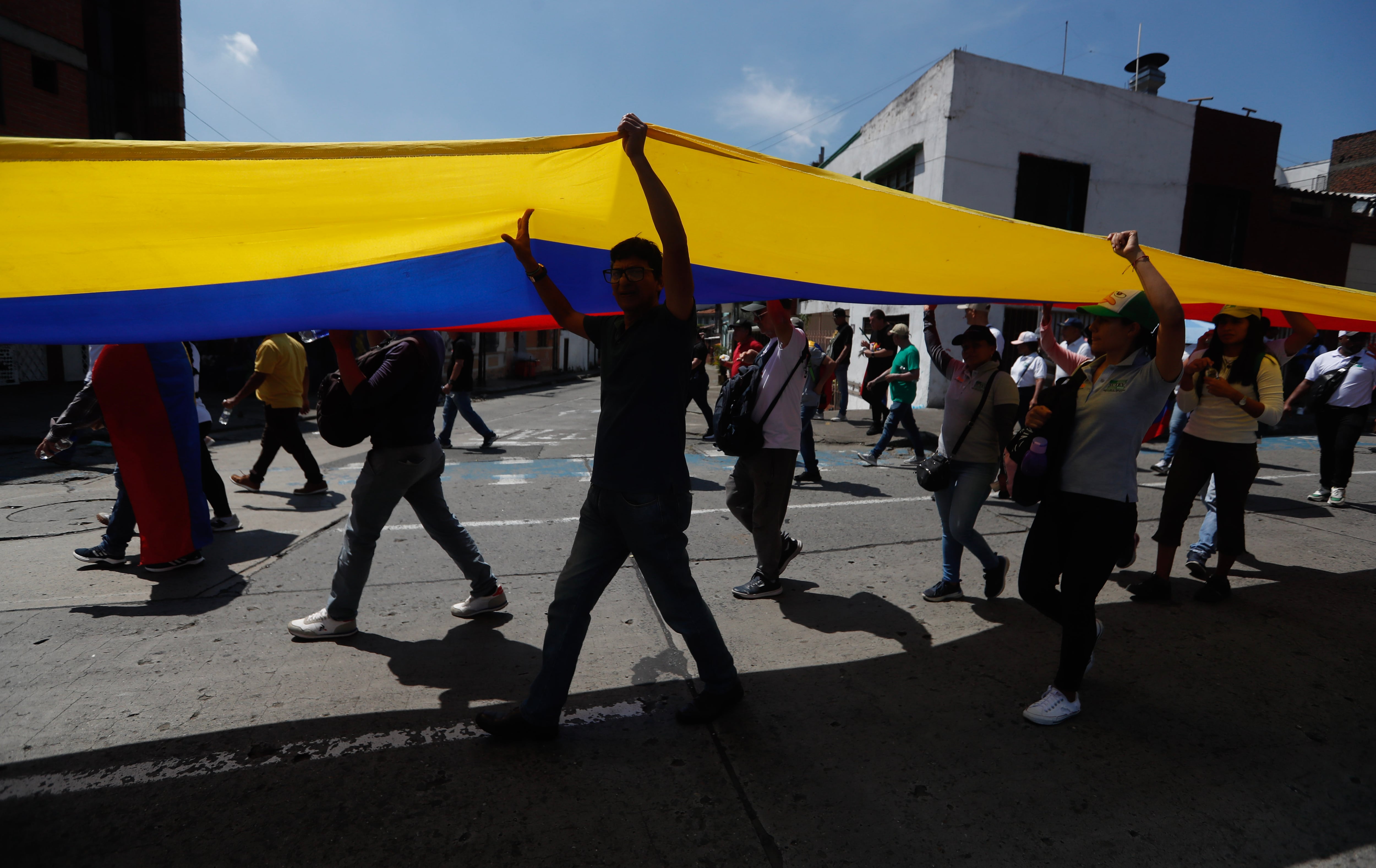 Ciudadanos colombianos cargando la bandera del país. Foto: EFE.