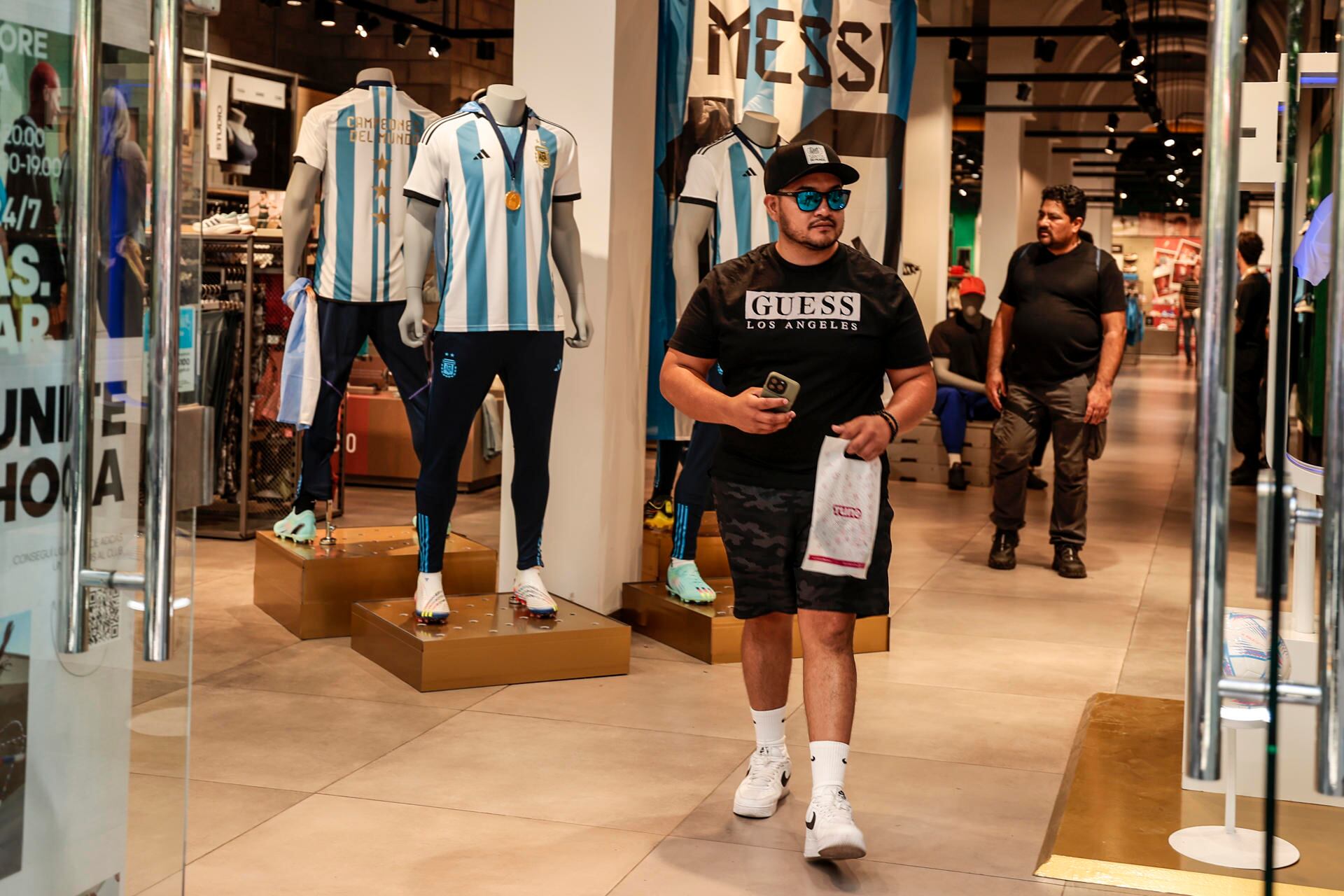 AME2703. BUENOS AIRES (ARGENTINA), 26/12/2022.- Aficionados de la selección argentina de fútbol acuden a una tienda a comprar la nueva camiseta de la selección con las tres estrellas y el escudo de campeones del mundo, hoy, en Buenos Aires (Argentina). La nueva camiseta de la Albiceleste, que incluye las tres estrellas sobre el escudo y el parche de la FIFA que acredita a la campeona del mundo, salió este lunes a la venta en Argentina en medio de la resaca por la celebración del título logrado en Qatar 2022. EFE/ Juan Ignacio Roncoroni