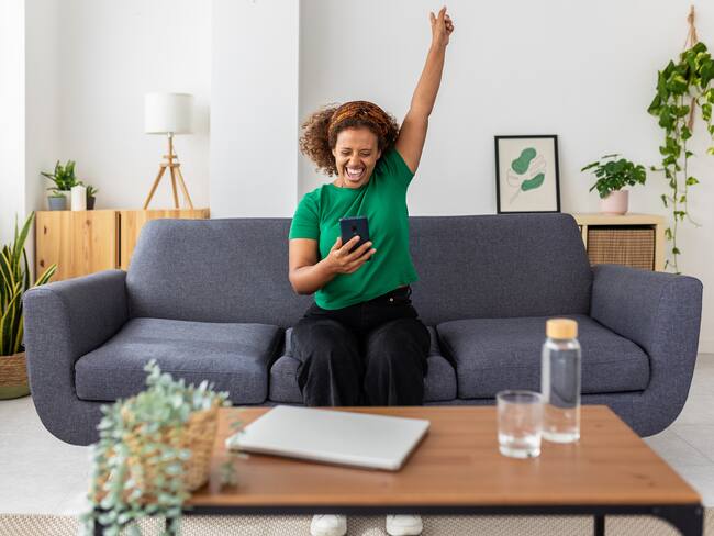 Excited young african woman celebrating success looking mobile phone screen