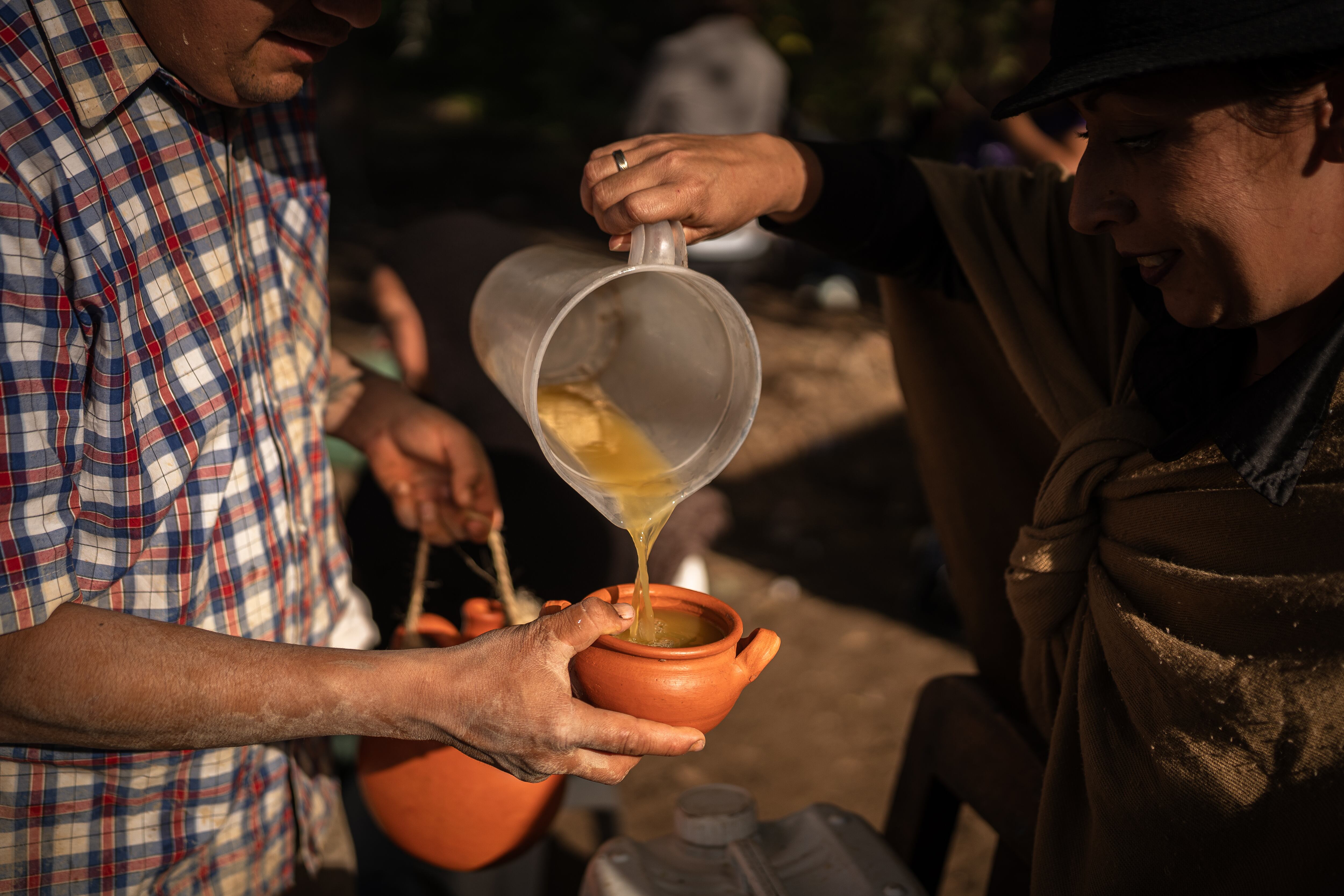 JENESANO, COLOMBIA - AUGUST 19: People Drink guarapo, a traditional alcoholic drink, during a match as part of the 2024 'Botas, Ruana y Sombrero Festival' on August 19, 2024 in Jenesano, Colombia. During the four-day festival, residents of different towns of the Boyacá department gather to be part of a football tournament where players wear boots, the traditional ruana (woollen fabric) and a sombrero (hat). The tournament has female and male categories and people of all ages can participate. The activities are not only focused on football but also on regional cultural expressions. (Photo by Diego Cuevas/Getty Images)