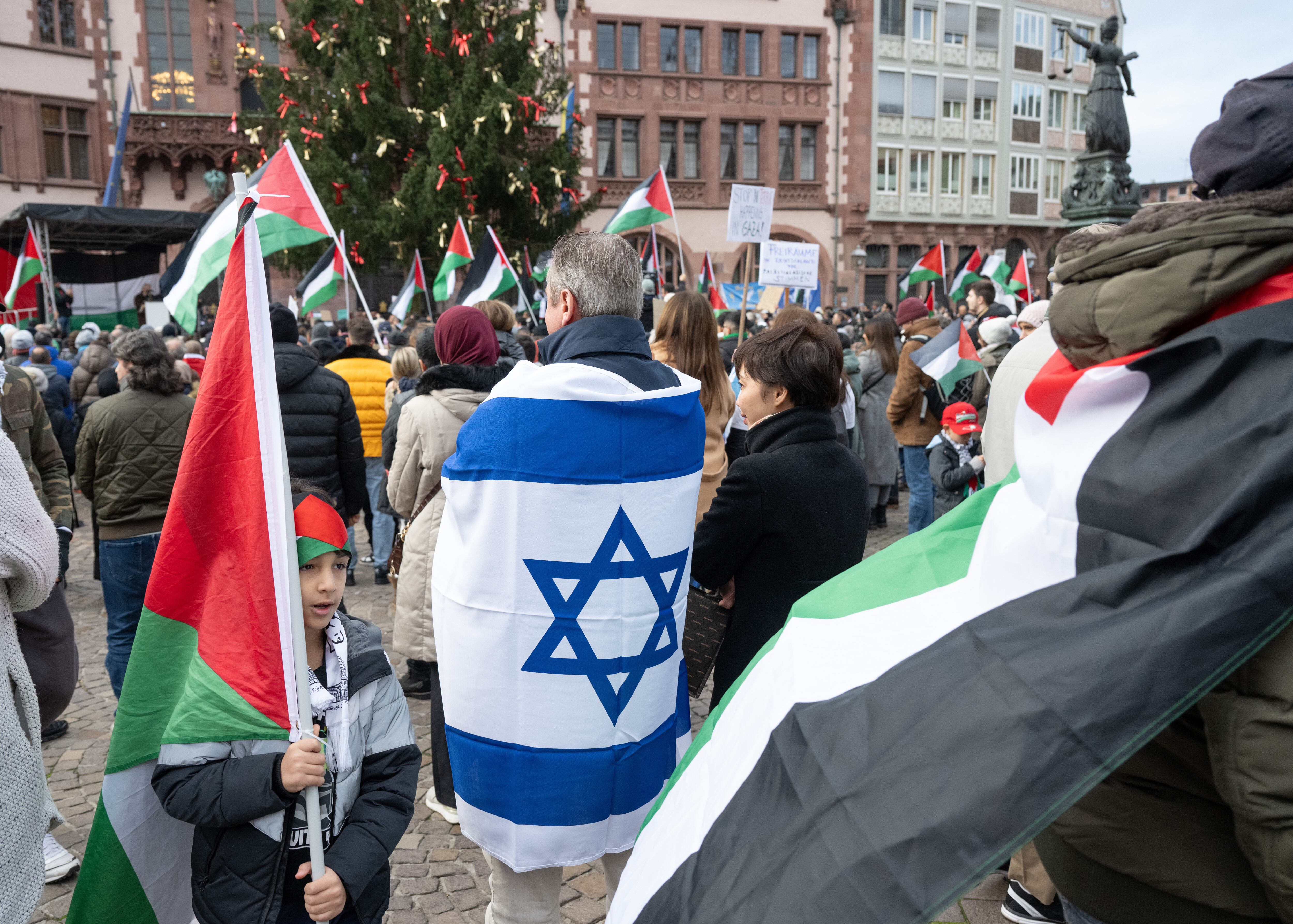 12 November 2023, Hesse, Frankfurt/Main: A man with an Israeli flag stands among pro-Palestinian demonstrators at a rally on the Römerberg. The rally is taking place under the slogan "Peace and justice in the Middle East". Photo: Boris Roessler/dpa (Photo by Boris Roessler/picture alliance via Getty Images)