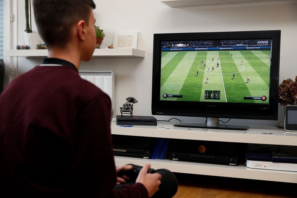 PARIS, FRANCE - DECEMBER 19: In this photo illustration a gamer plays the video game ‘FIFA 19' developed and published by Electronic Arts (EA) on a Sony PlayStation game console PS4 Pro on December 19, 2018 in Paris, France. FIFA 19 is a soccer video game released on September 28, 2018. This is the twenty-sixth installment of the FIFA franchise developed by EA. (Photo Illustration by Chesnot/Getty Images)