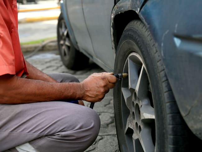 Hombre calibrando la presión de las llantas de su carro (Getty Images)