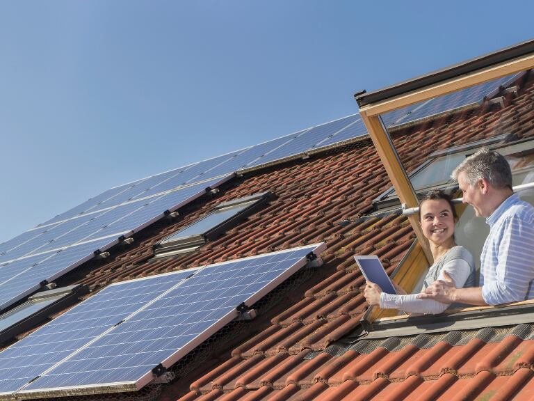 Personas usando un computador y al fondo paneles solares en un techo (Foto vía Getty Images)