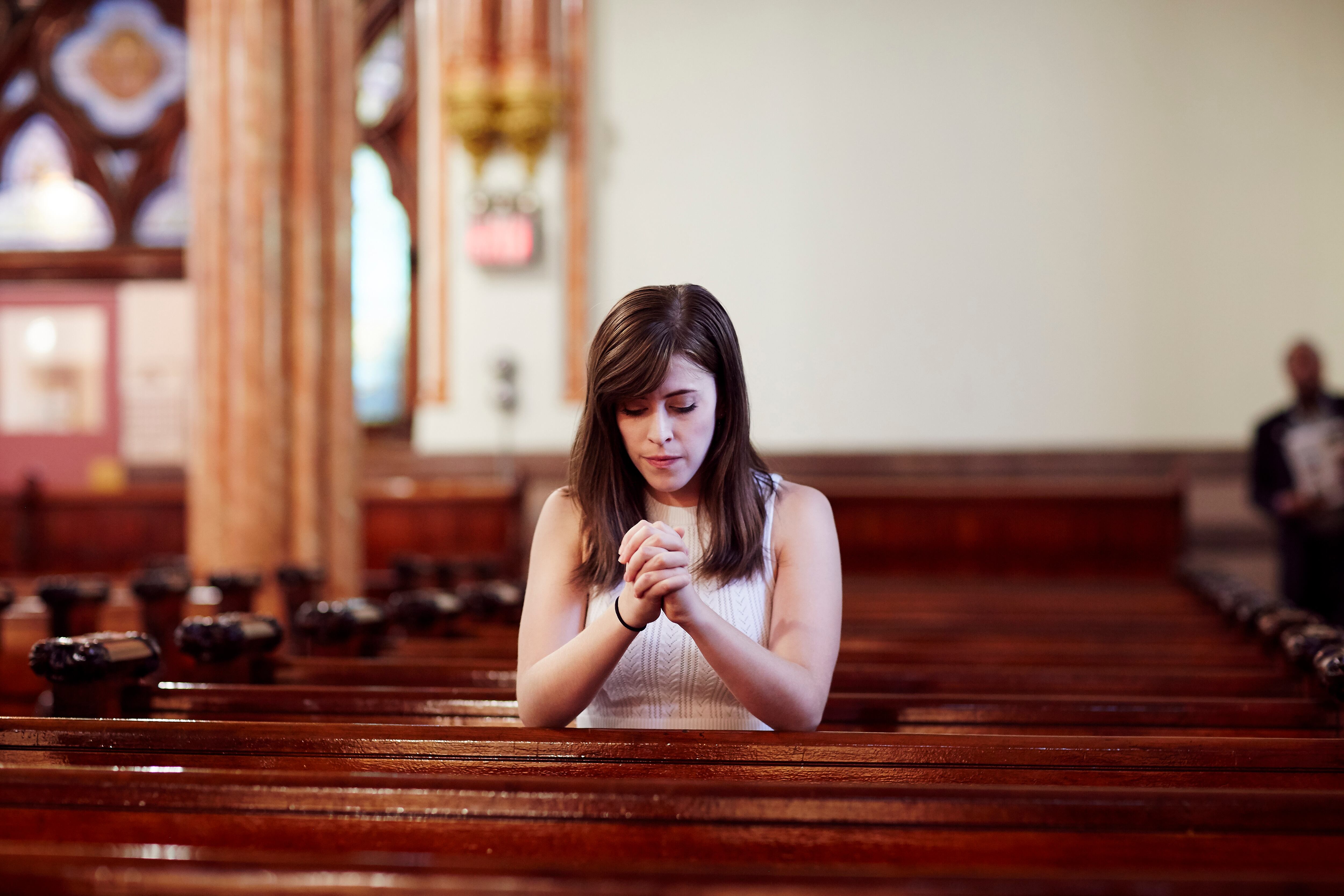 Mujer orando en una iglesia (GettyImages)