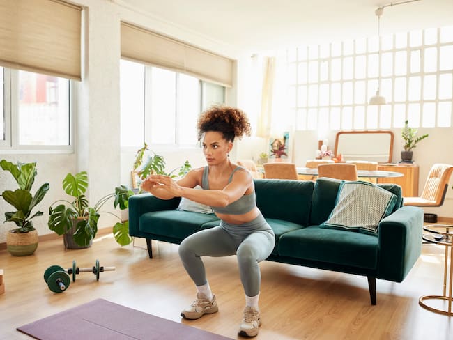Mujer realizando ejercicios en casa (Foto vía Getty Images)