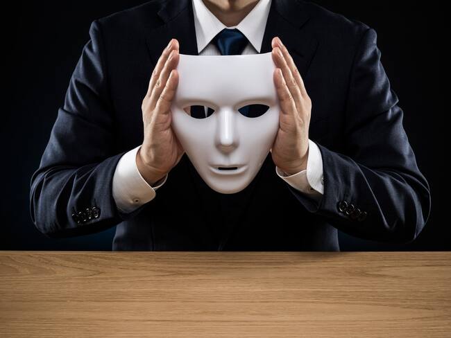 Man in a suit removes his mask