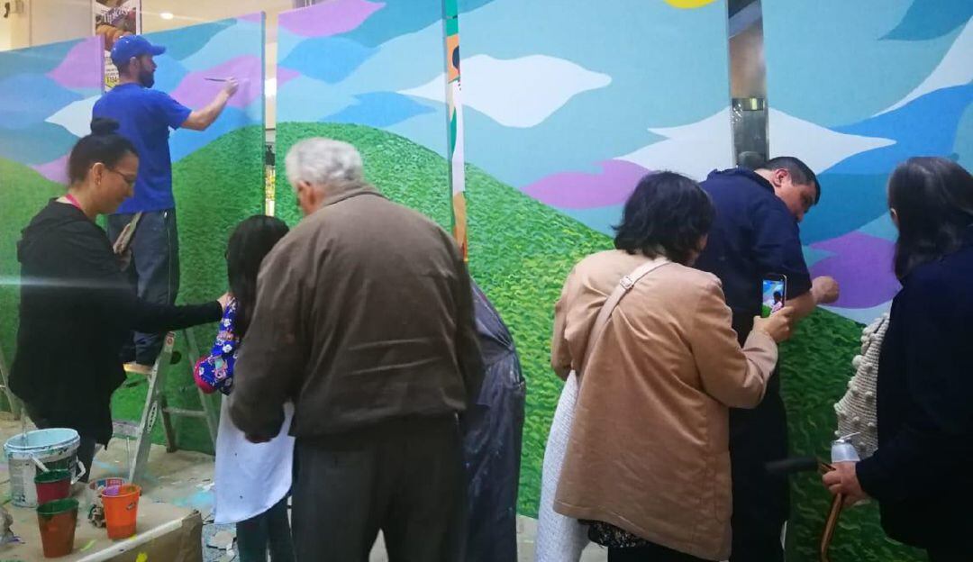 La gente del común también ayudan en la elaboración del mural. 