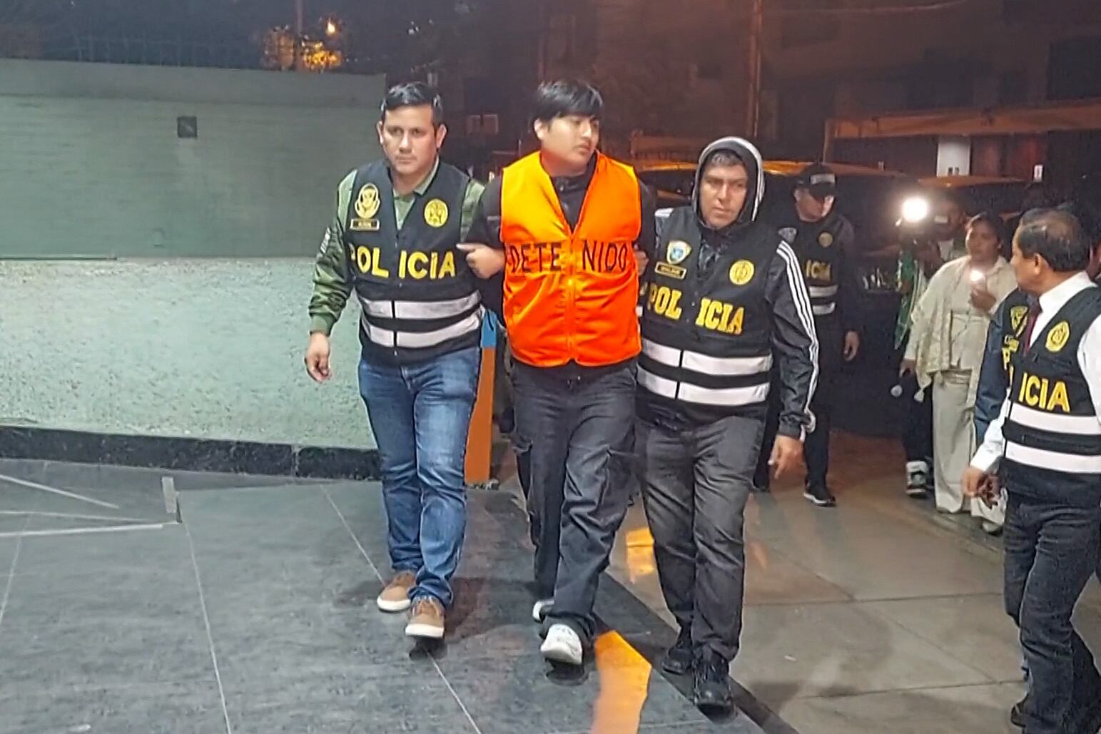 Frame grab from video footage by AFP TV shows the suspected mastermind behind the brutal murders of three young women in a live-streamed attack in Argentina, identified as "Peque�o J," escorted by police officers arriving at the Peruvian police Anti-Drug HQ in Lima on September 30, 2025. The suspected mastermind, Tony Janzen Valverde, "Peque�o J," is a Peruvian national, about 20 years old, and is alleged to operate a drug gang in the Zavaleta neighborhood of Buenos Aires. (Photo by Carlos MANDUJANO / AFPTV / AFP)