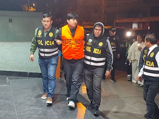 Frame grab from video footage by AFP TV shows the suspected mastermind behind the brutal murders of three young women in a live-streamed attack in Argentina, identified as "Peque�o J," escorted by police officers arriving at the Peruvian police Anti-Drug HQ in Lima on September 30, 2025. The suspected mastermind, Tony Janzen Valverde, "Peque�o J," is a Peruvian national, about 20 years old, and is alleged to operate a drug gang in the Zavaleta neighborhood of Buenos Aires. (Photo by Carlos MANDUJANO / AFPTV / AFP)