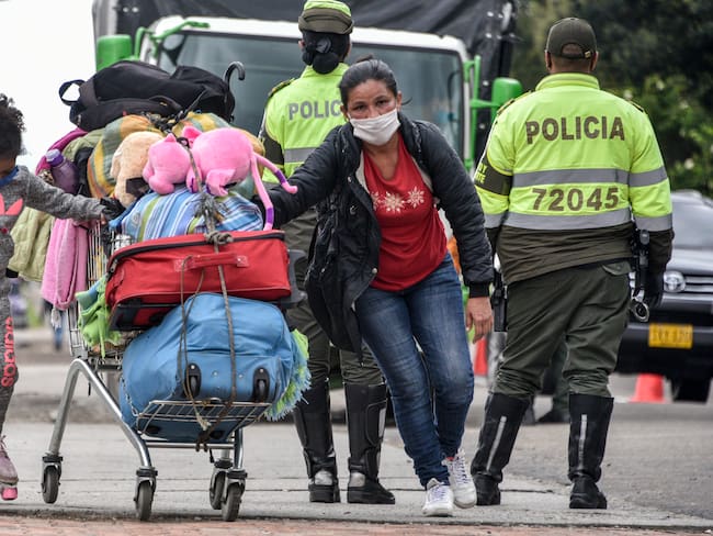 Migrantes venezolanos caminan con sus pertenencias en vías de Bogotá (Colombia).