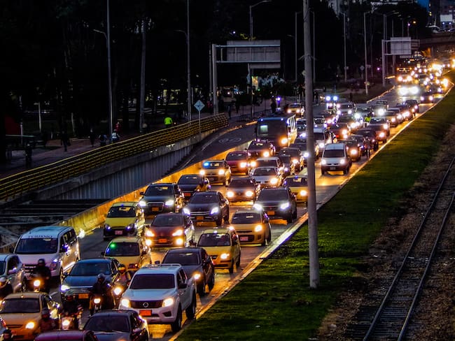 Atasco de tráfico en una avenida con coches y ferrocarril a un lado en Bogotá Colombia. Vía Getty Images.