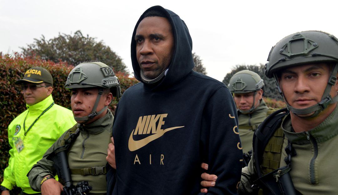 El exjugador de la selección nacional de fútbol de Colombia Jhon Viafara (C) es fuertemente escoltado a su llegada a Bogotá luego de ser arrestado bajo sospecha de tráfico de drogas, como miembro de un cartel que envía drogas a los Estados Unidos, el 20 de marzo de 2019.