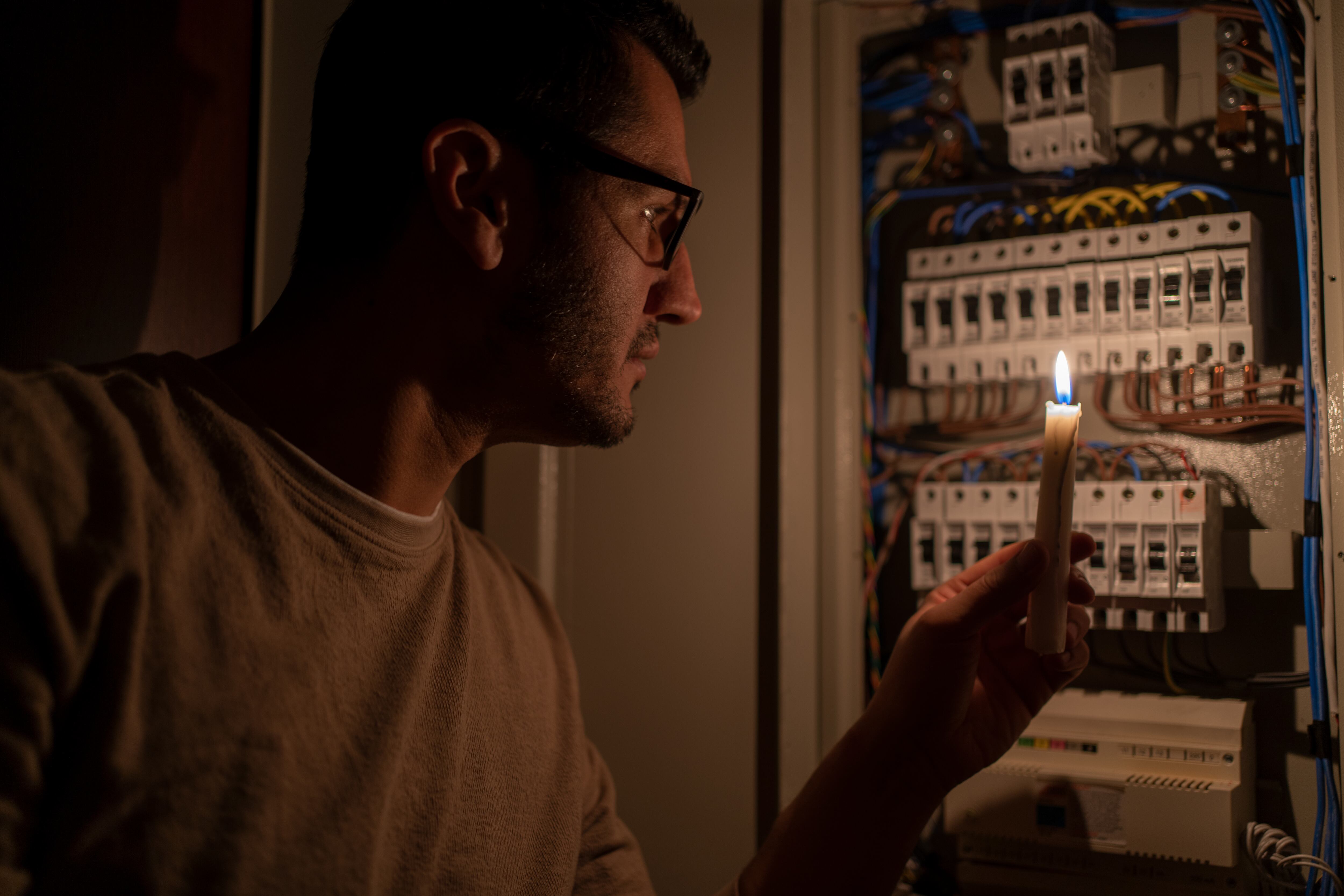 Hombre observando la caja eléctrica de su hogar con una vela porque se fue la luz (Foto vía Getty Images)
