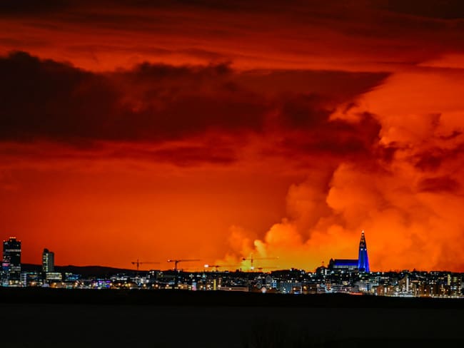 El horizonte de Reykjavik tiene como telón de fondo un cielo de color naranja debido a la lava fundida que fluye desde una fisura en la península de Reykjanes al norte de la ciudad evacuada de Grindavik, al oeste de Islandia, el 16 de marzo de 2024. Lava arrojada el sábado desde un nuevo volcán fisura en la península de Reykjanes en Islandia- (Foto de Halldor KOLBEINS/AFP) (Foto de HALLDOR KOLBEINS/AFP vía Getty Images)