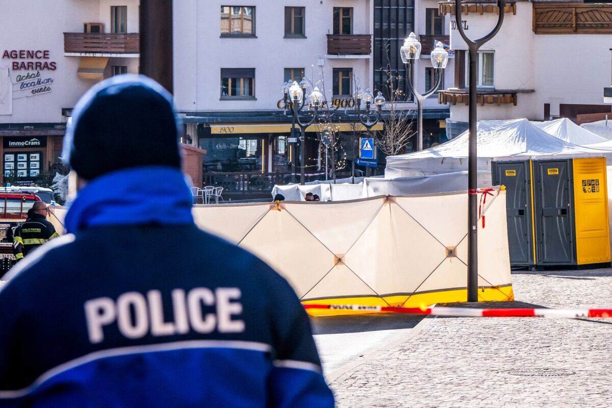 A police officer patrols on front of folding screens set up around the Constellation bar in the luxury Alpine ski resort town of Crans-Montana, on January 1, 2026 after a fire ripped through the venue during the New Year's Eve celebrations. Several dozen people are presumed dead and around 100 injured after a fire ripped through a crowded bar in the luxury Swiss ski resort of Crans-Montana, Swiss police said on January 1, 2026. Police, firefighters and rescuers rushed to the popular resort, which is set to host the Ski World Cup from January 30, after the fire broke out in the early hours of New Year's Day. (Photo by MAXIME SCHMID / AFP)