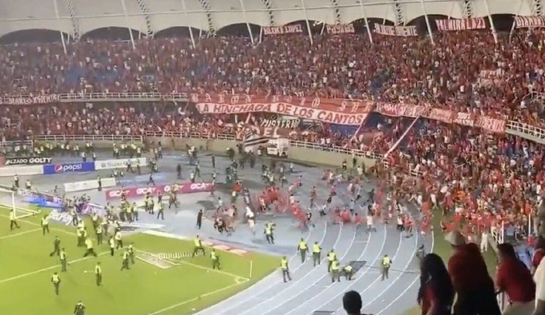 Los hinchas de la tribuna sur ingresan al terreno de juego en el partido del América ante Nacional.