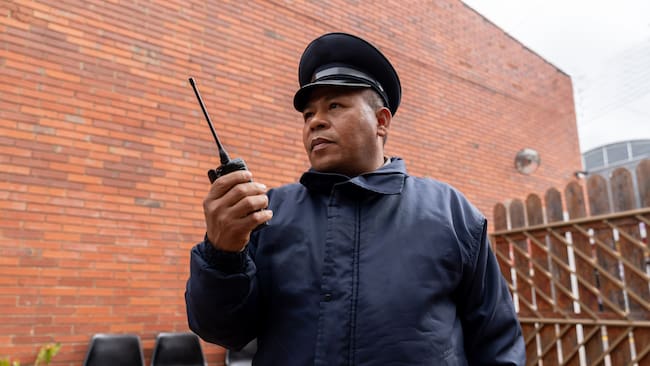 Hombre vigilante de seguridad con su radio en la mano (Getty Images)