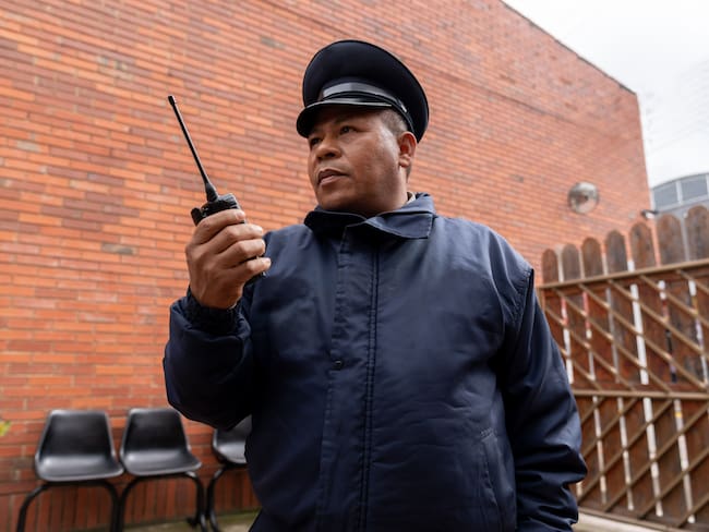 Hombre vigilante de seguridad con su radio en la mano (Getty Images)