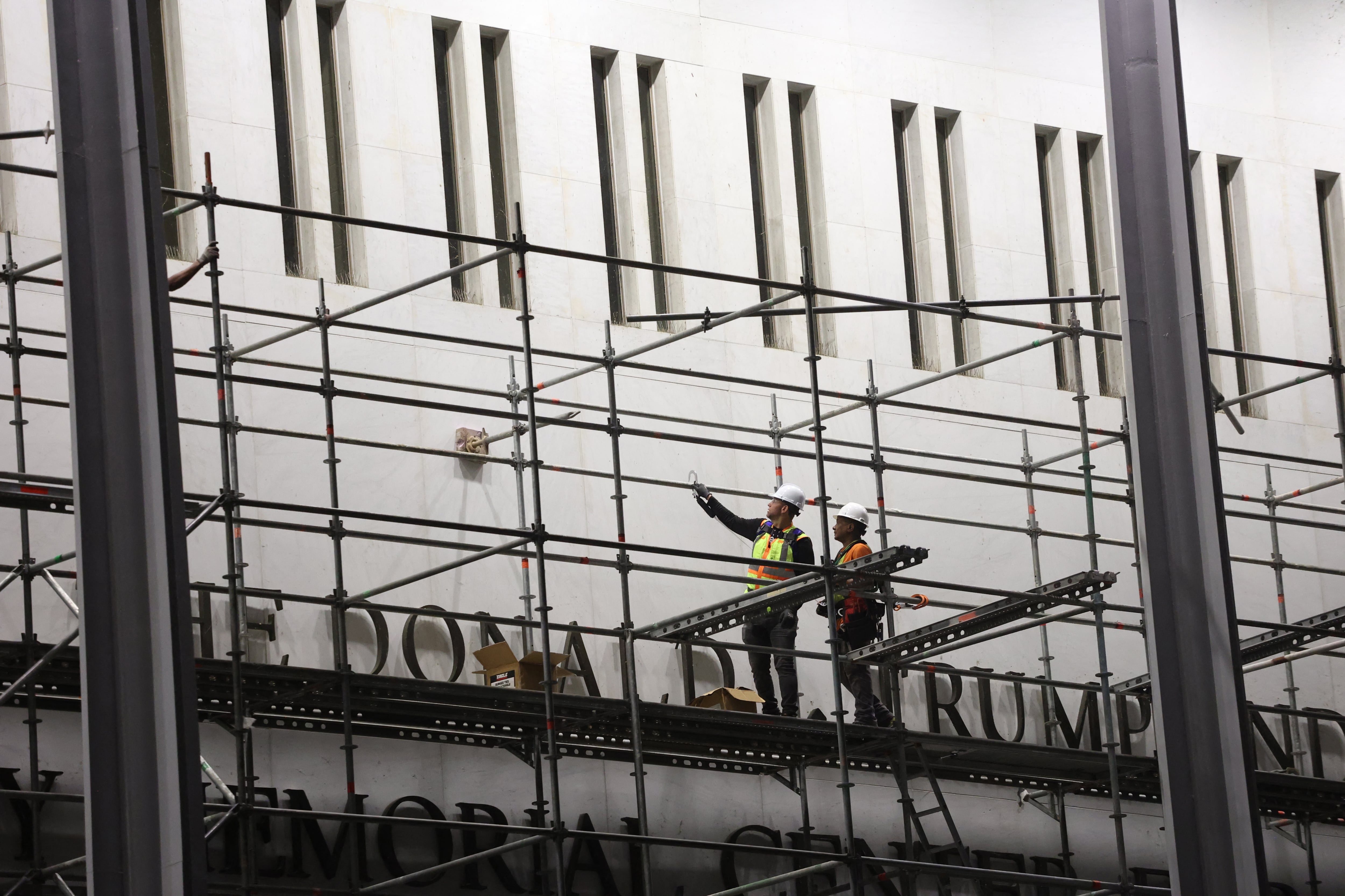 Workers build scaffolding near the signage for the "Donald J. Trump and John F. Kennedy Memorial Center for the Performing Arts" in Washington, DC, early on June 13, 2026. A US federal judge on June 12 rejected a bid by the board of the Kennedy Center and the Justice Department to halt the removal of President Donald Trump's name from the performing arts venue. District Judge Christopher Cooper, in a ruling last month, ordered Trump's name taken off the iconic building in the nation's capital by Friday, June 12, 2026. (Photo by Alex WROBLEWSKI / AFP)