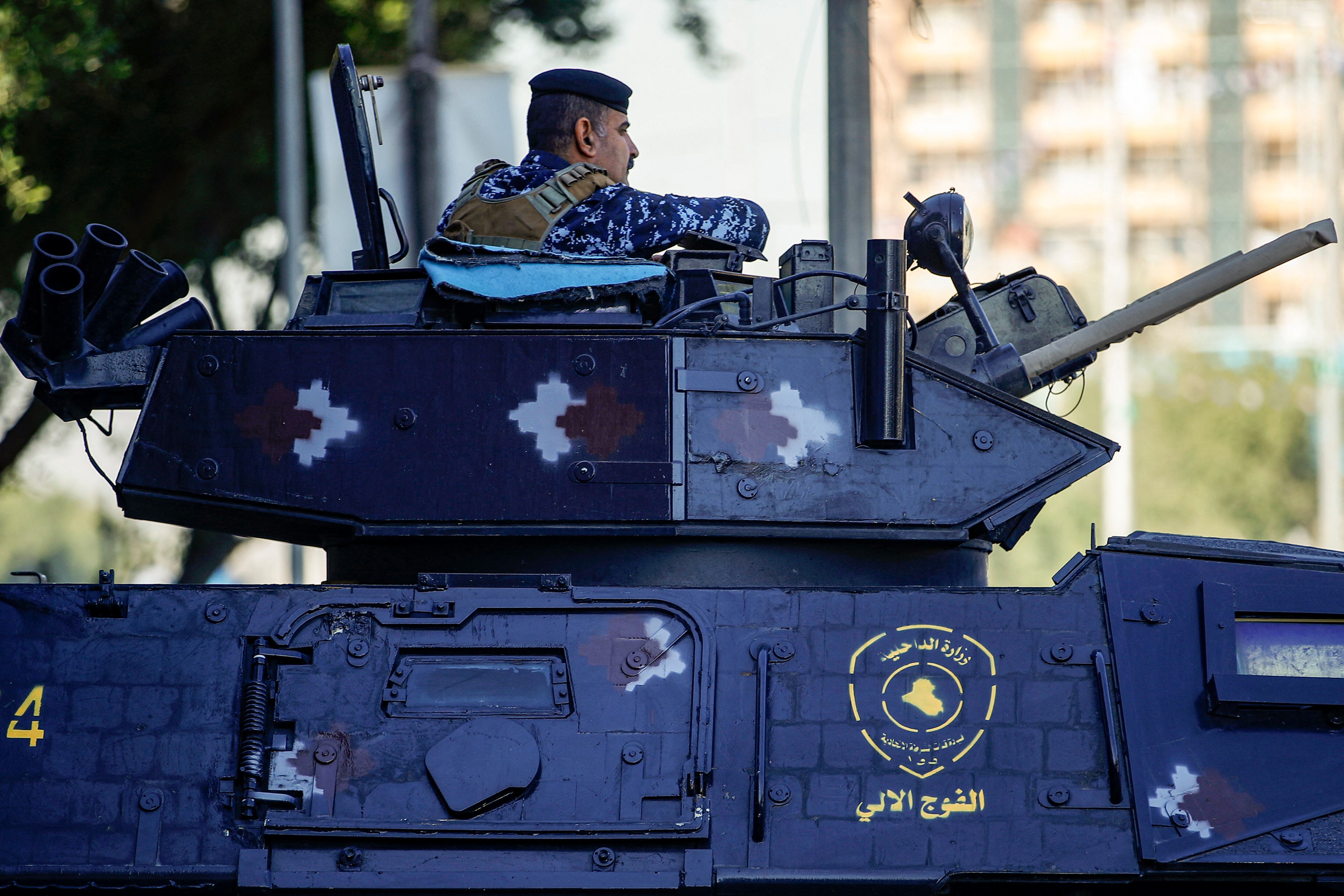 A member of the Iraqi security forces sits in the hatch of a turret of an armoured vehicle deployed along a street in Baghdad on December 26, 2023. Iraq on December 26 denounced US air strikes in the country as a "hostile act" after the Pentagon said it had targeted three sites used by pro-Iran forces after coming under fire. The government said the strikes that killed one member of the security forces and wounded 18 other people, including civilians, were an "unacceptable attack on Iraqi sovereignty" that damaged bilateral relations. (Photo by AHMAD AL-RUBAYE / AFP) (Photo by AHMAD AL-RUBAYE/AFP via Getty Images)