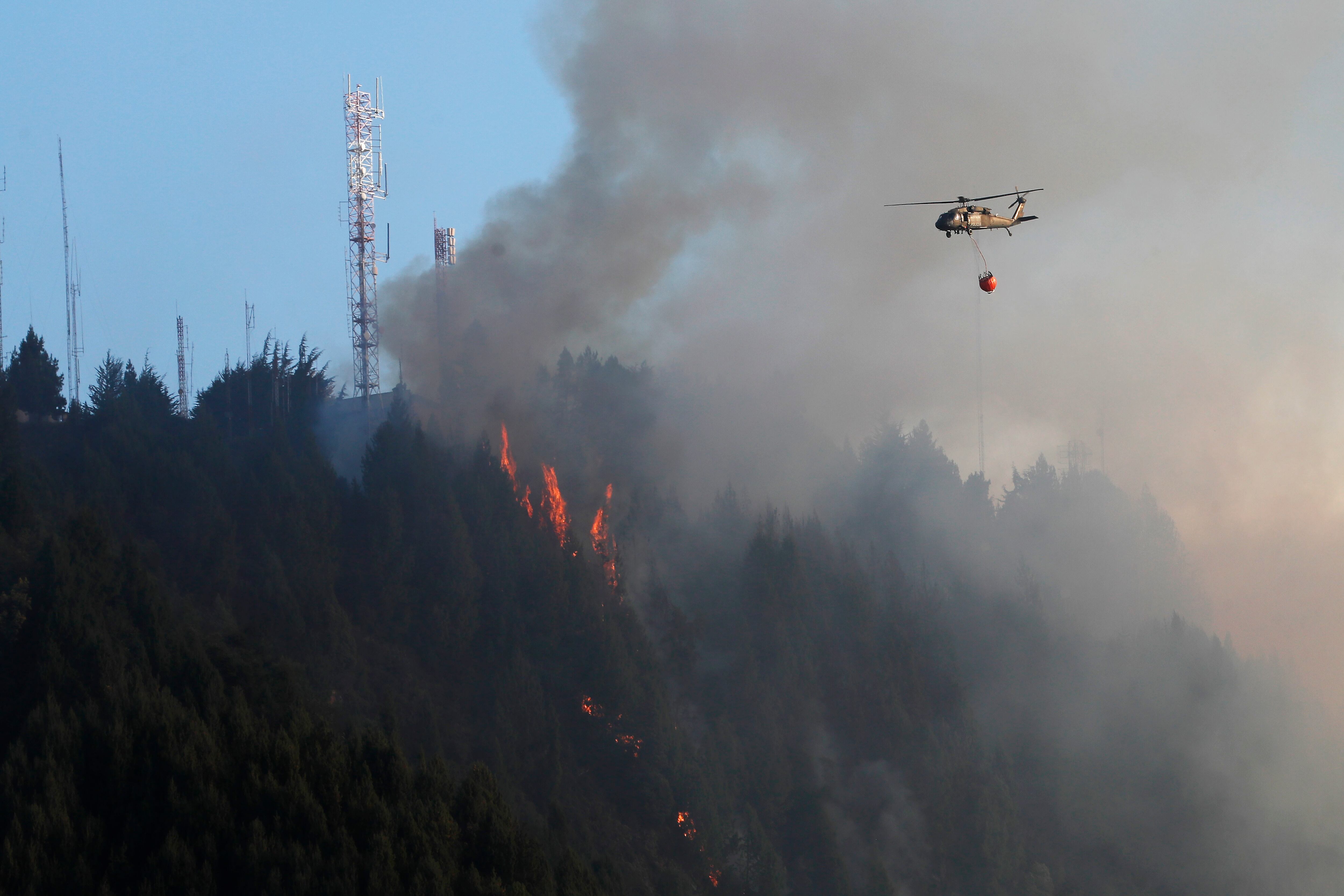 BOG400. BOGOTÁ (COLOMBIA), 24/01/2024.- Un helicóptero combate hoy un incendio forestal en el cerro El Cable, en Bogotá (Colombia). Un nuevo incendio, que ahonda la crisis medioambiental en Colombia, comenzó este miércoles en los cerros orientales de Bogotá, esta vez en uno conocido como El Cable y en donde las autoridades locales tratan de apagar las llamas. EFE/ Carlos Ortega