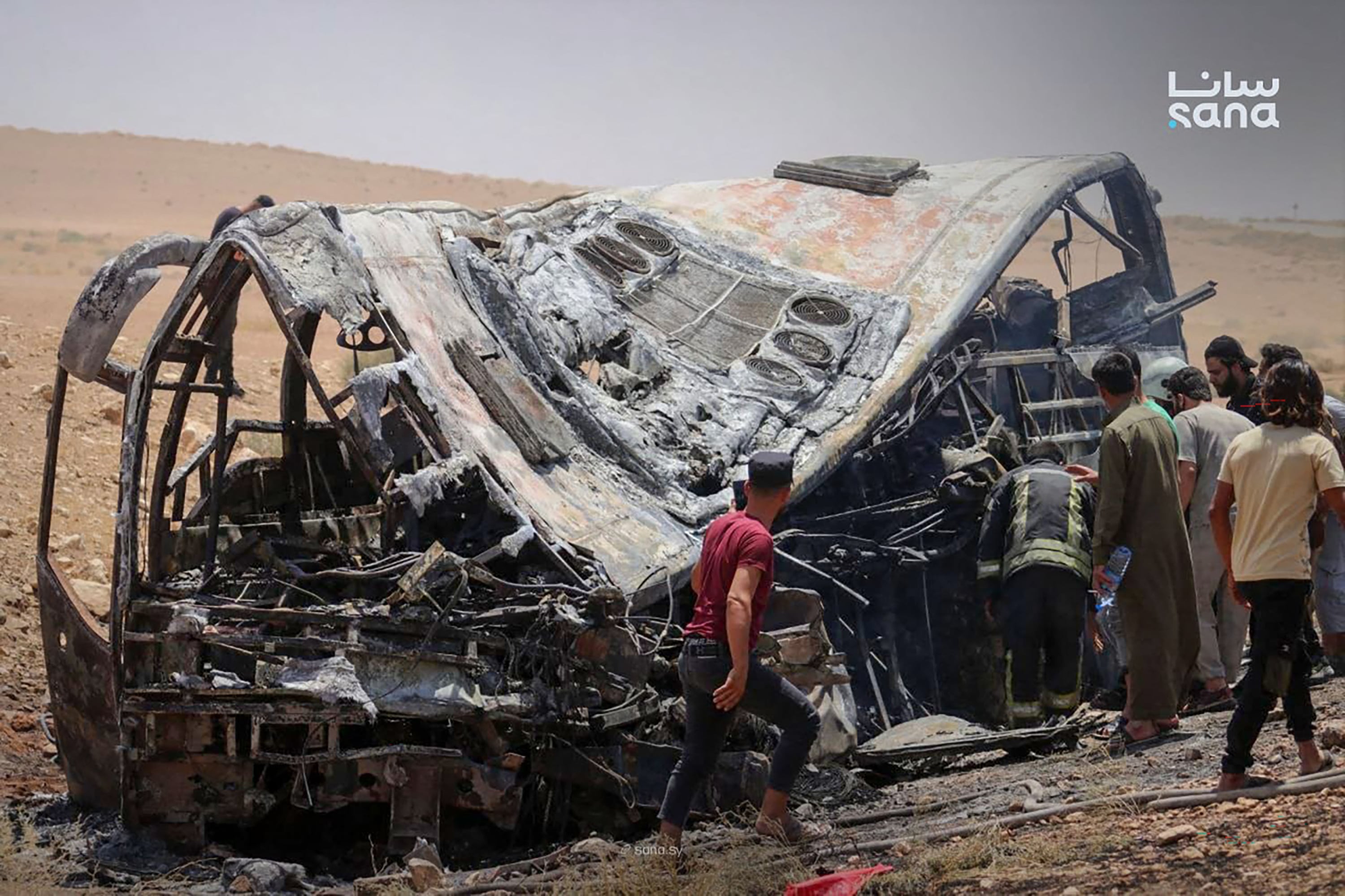 Esta fotografía, distribuida por la agencia oficial de noticias siria SANA el 25 de julio de 2026, muestra a personas y personal de emergencia inspeccionando los daños en el lugar de la colisión de dos autobuses de pasajeros en la carretera Damasco-Deir Ezzor, entre las zonas de Sukhna y Palmira. El número de muertos en el accidente ocurrido el 25 de julio en una región desértica del centro-este de Siria ascendió a 35, según informaron los medios estatales. La agencia de noticias SANA, citando a un funcionario del Ministerio de Salud, indicó que 30 personas más resultaron heridas, tras haber informado previamente de un balance preliminar de 19 fallecidos. (Foto de SANA / AFP) / == USO EDITORIAL RESTRINGIDO - CRÉDITO OBLIGATORIO "AFP PHOTO / HO / SANA" - PROHIBIDO SU USO EN CAMPAÑAS DE MARKETING O PUBLICIDAD - DISTRIBUIDO COMO SERVICIO A LOS CLIENTES ==