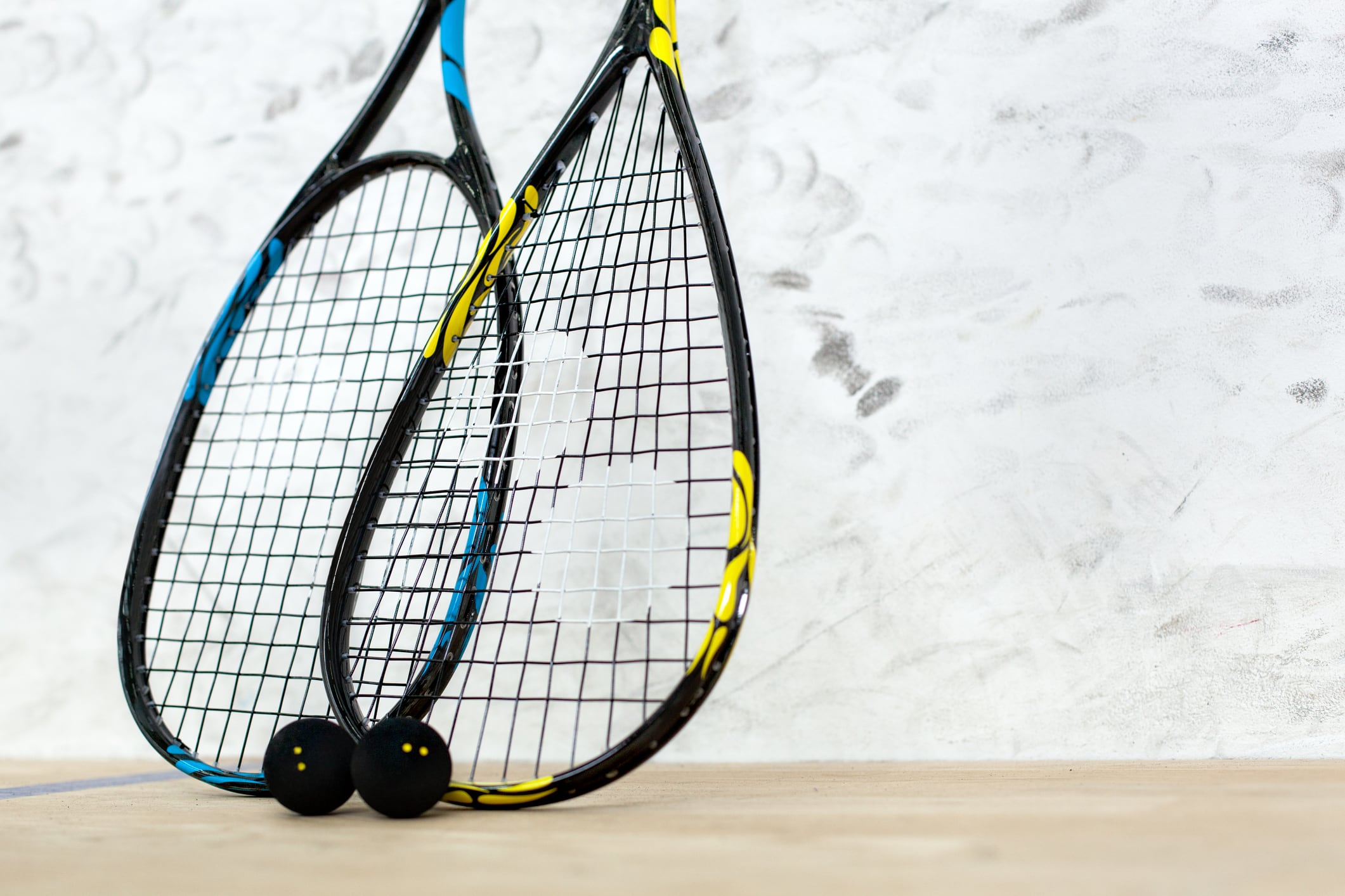 Close up of two tennis rackets and black balls over white wall background - sport, fitness, healthy lifestyle and objects concept