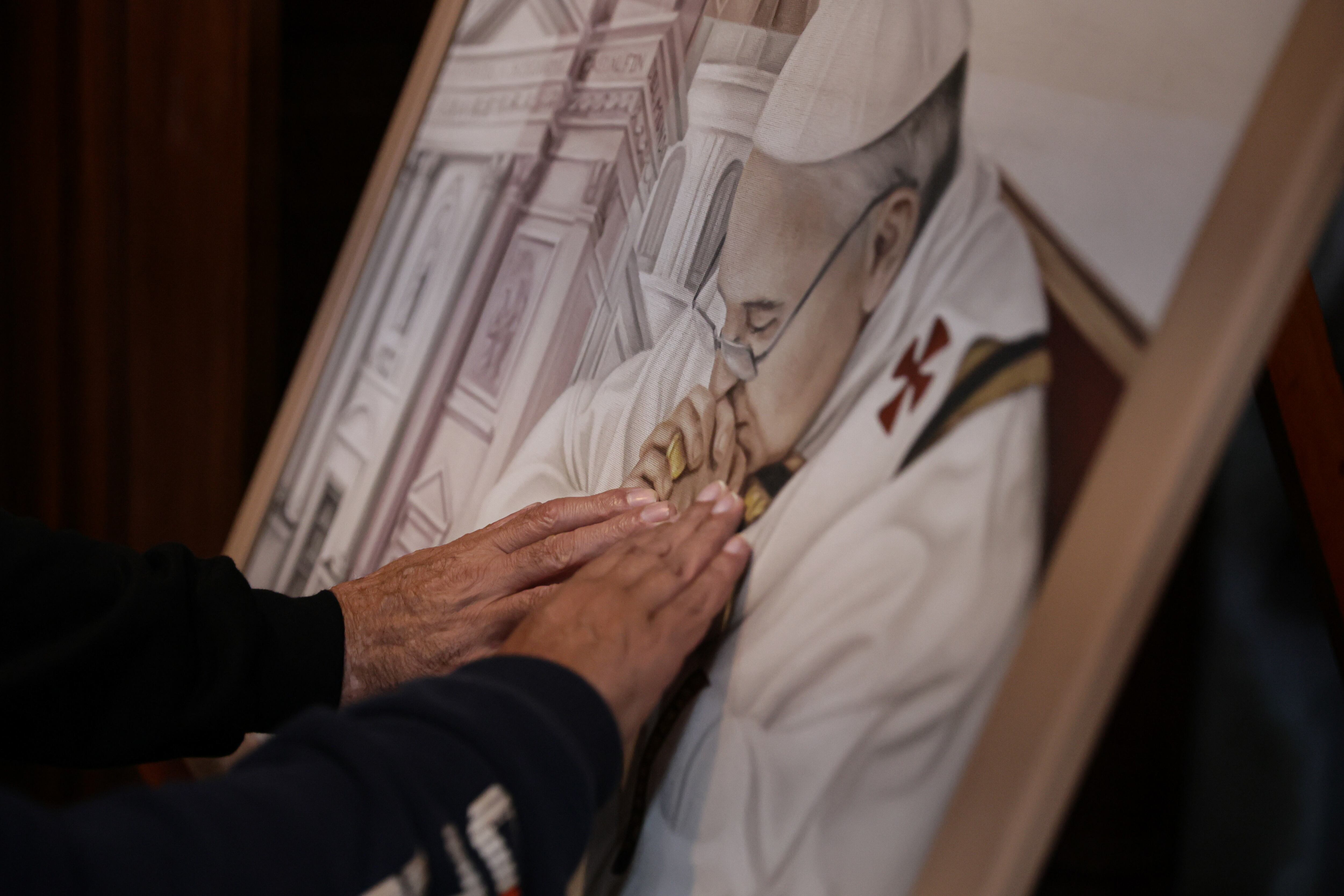 Personas tocan una imagen del papa Francisco este lunes en la Basílica San José de Flores, lugar en el que Francisco 'Recibió el llamado divino', en Buenos Aires (Argentina). Argentina, la tierra que hace 88 años vio nacer a Jorge Mario Bergoglio y que en 2013 lo vio marcharse para ocupar la silla de Pedro, le despide entre la congoja, la gratitud y el reconocimiento a quien quedará en la historia como el primer sumo pontífice latinoamericano y el 'papa de los descartados'. EFE/Stringer