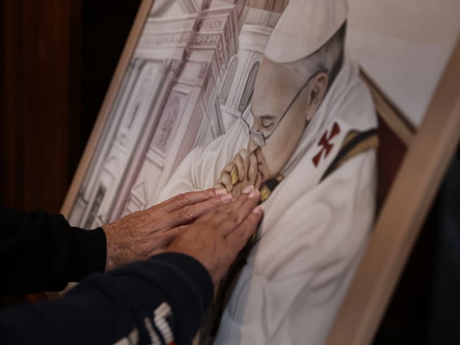 AME1280. BUENOS AIRES (ARGENTINA), 21/04/2025.- Personas tocan una imagen del papa Francisco este lunes en la Basílica San José de Flores, lugar en el que Francisco 'Recibió el llamado divino', en Buenos Aires (Argentina). Argentina, la tierra que hace 88 años vio nacer a Jorge Mario Bergoglio y que en 2013 lo vio marcharse para ocupar la silla de Pedro, le despide entre la congoja, la gratitud y el reconocimiento a quien quedará en la historia como el primer sumo pontífice latinoamericano y el 'papa de los descartados'. EFE/Stringer
