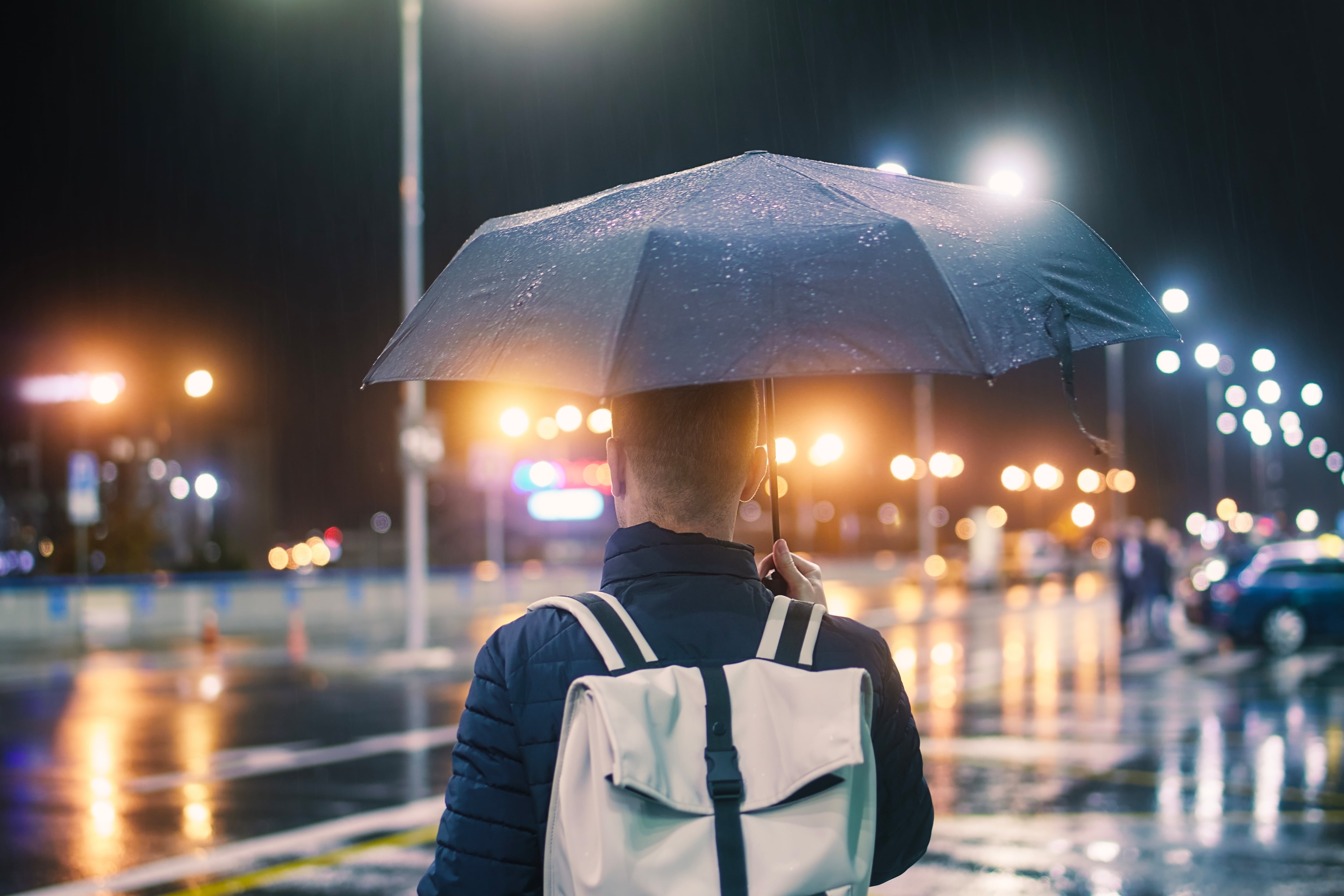 Un hombre sosteniendo un paraguas mojado en una calle de la ciudad bajo la lluvia, por la noche. - Foto Getty Images