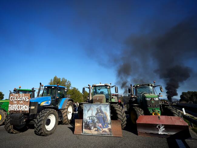 GRAFCAT9705. PONTÓS (GIRONA), 13/02/2024.- Decenas de tractores mantienen cortada en ambos sentidos la AP-7 a la altura de Pontós (Girona), este martes, cuando centenares de tractores mantienen desde las 07.00 horas de este martes marchas lentas desde diversos puntos de Cataluña con la intención de bloquear los accesos a Mercabarna y el puerto de Tarragona, y cortar la AP-7 en la frontera francesa. EFE/David Borrat