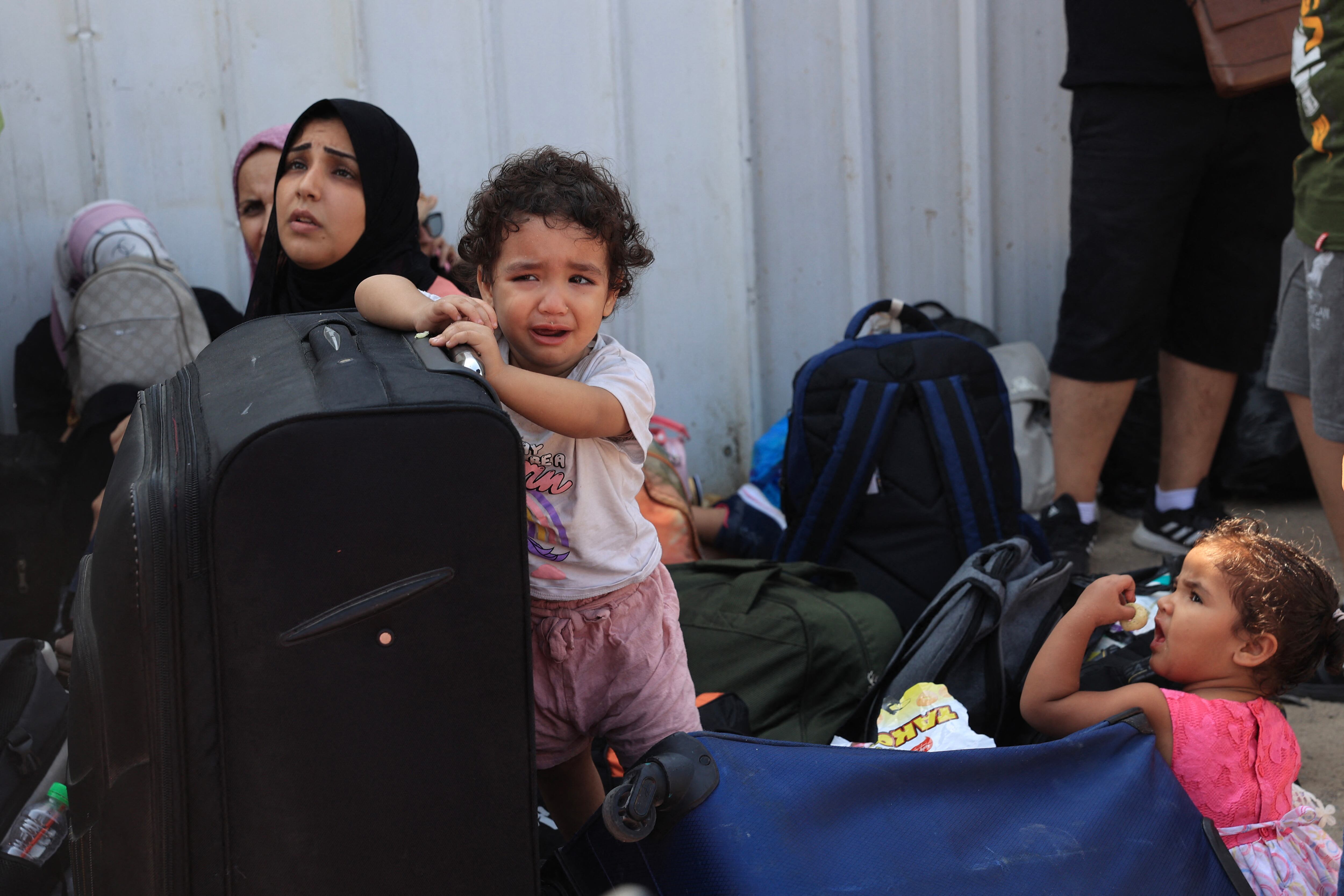 A child cries as Palestinians with foreign passports wait at the Rafah gate hoping to cross into Egypt as Israel's attacks on the Gaza Strip continues on October 14, 2023. International aid groups and major powers have pleaded with Israel to set up safe zones in Gaza where thousands struggled on October 14 to get out of a major part of the Palestinian territory under threat of attack. (Photo by SAID KHATIB / AFP) (Photo by SAID KHATIB/AFP via Getty Images)