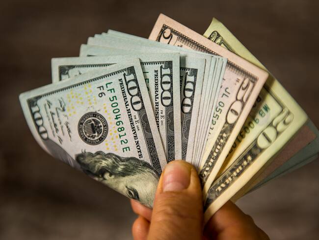 Hombre con muchos dólares en su mano (Getty Images)