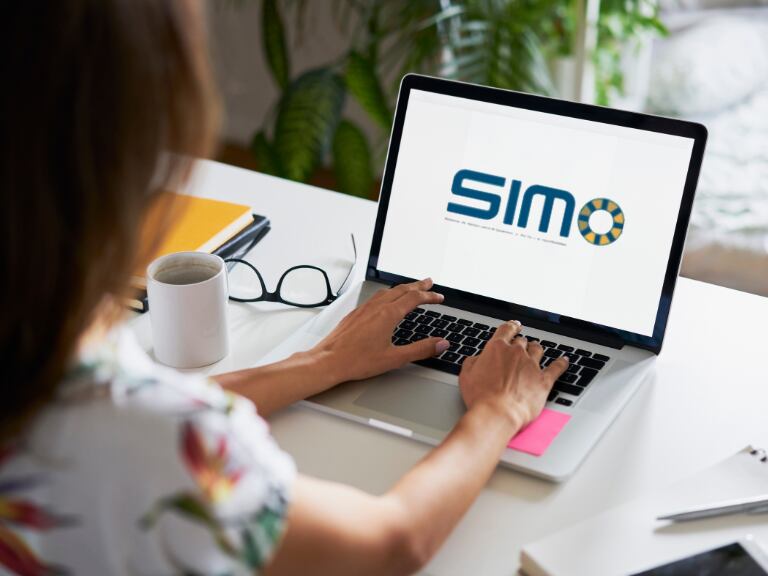 Persona navegando en un computador portátil con el logo de SIMO (Fotos vía Getty Images y COLPRENSA).