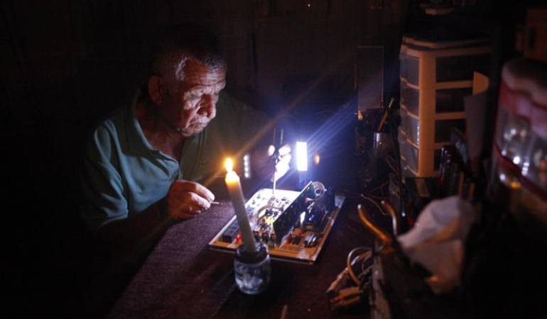 Un hombre repara un electrodoméstico durante un corte de luz en Venezuela.