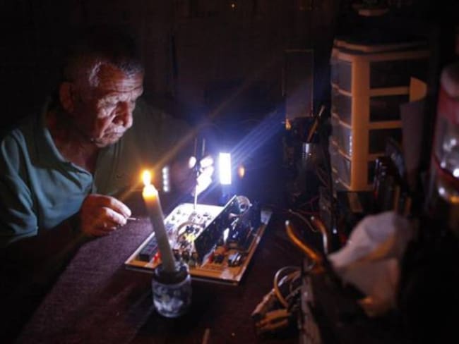 Un hombre repara un electrodoméstico durante un corte de luz en Venezuela.