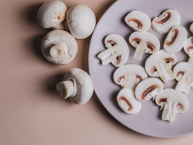 Close up Champiñones enteros y cortados en un plato (Getty Images)