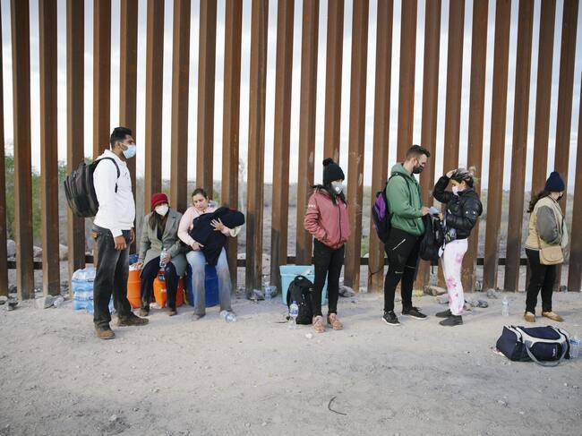 YUMA, ARIZONA , UNITED STATES - FEBRUARY 23: Asylum seekers from India, Cuba, and Colombia wait next to the USA border wall with Mexico, while being processed by USA border patrol in Yuma, Arizona, United States on February 22, 2022 . They wait for USA border patrol to arrive so they can turn themselves in. Yuma, Arizona. (Photo by Katie McTiernan/Anadolu Agency via Getty Images)