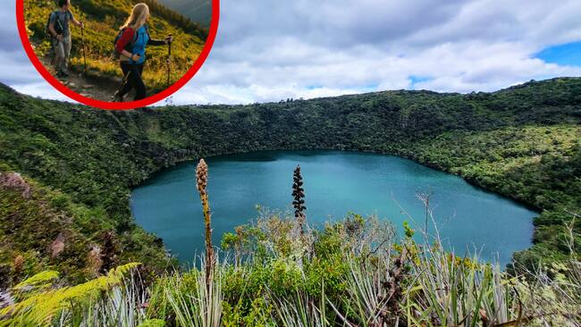 Laguna de Guatavita de fondo, y dos personas haciendo senderismo. (Foto: Getty Images)