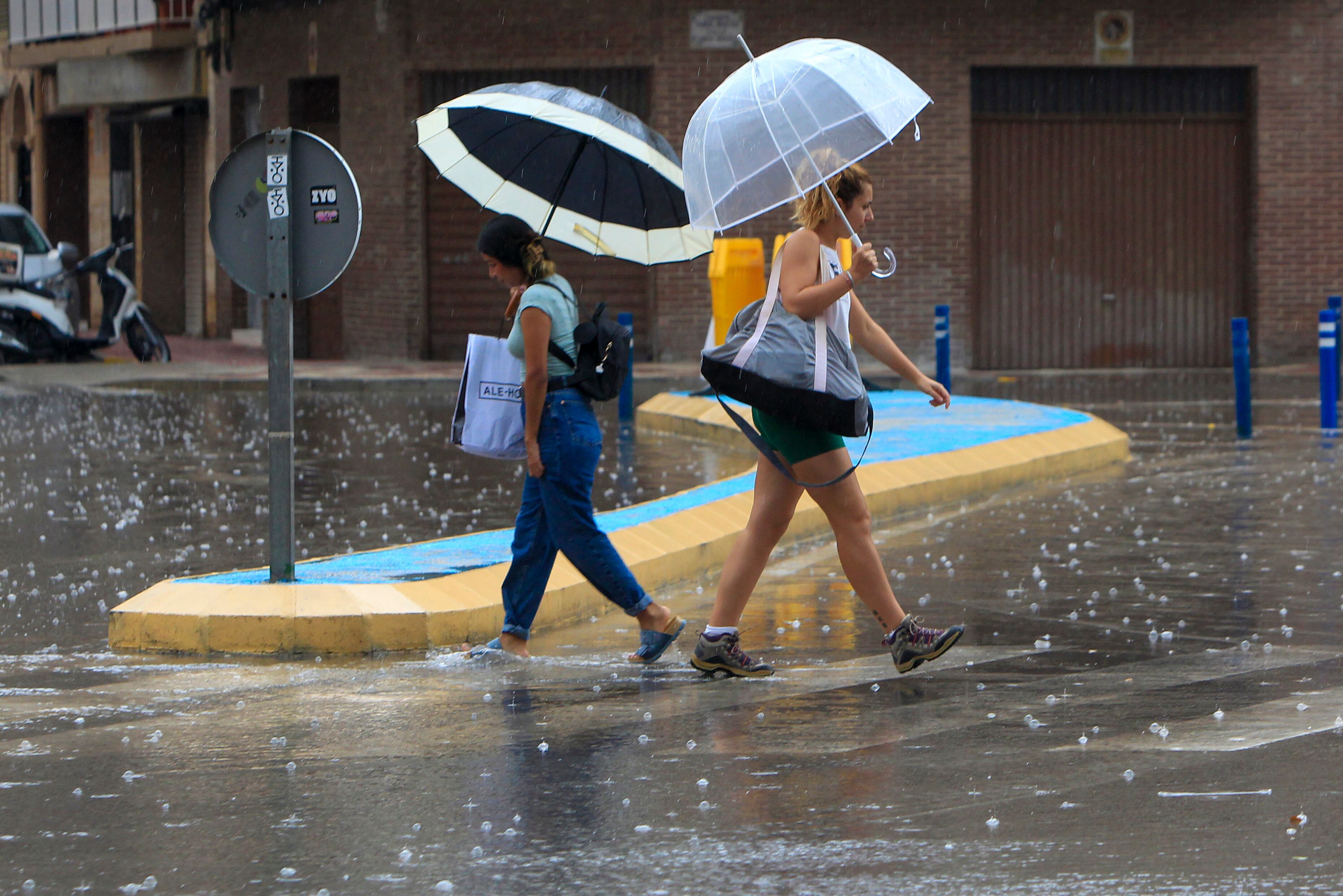FOTODELDÍA GRAFCVA2558. SANTA POLA (ALICANTE), 03/09/2024.- Dos personas cruzan una calle bajo la lluvia este martes en Santa Pola cuando la mayor parte del territorio de la Comunitat podría recibir este martes chubascos tormentosos localmente fuertes y acompañados de granizo. EFE/Morell