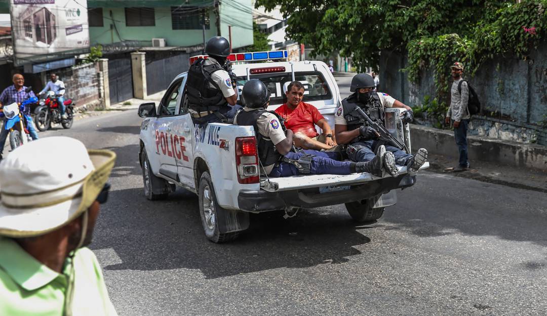 Una patrulla transporta a dos extranjeros golpeados por una turba que los acusó de portar cargadores de fusil y de hacer parte del comando que asesinó al presidente.