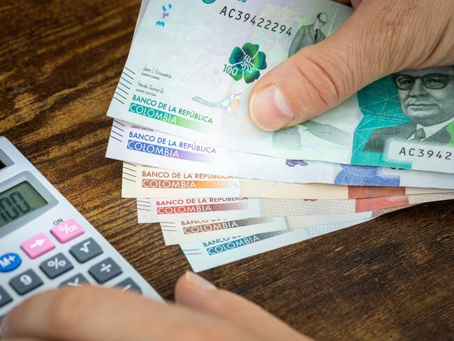 Hombre haciendo cuenta con billetes colombianos (Getty Images)
