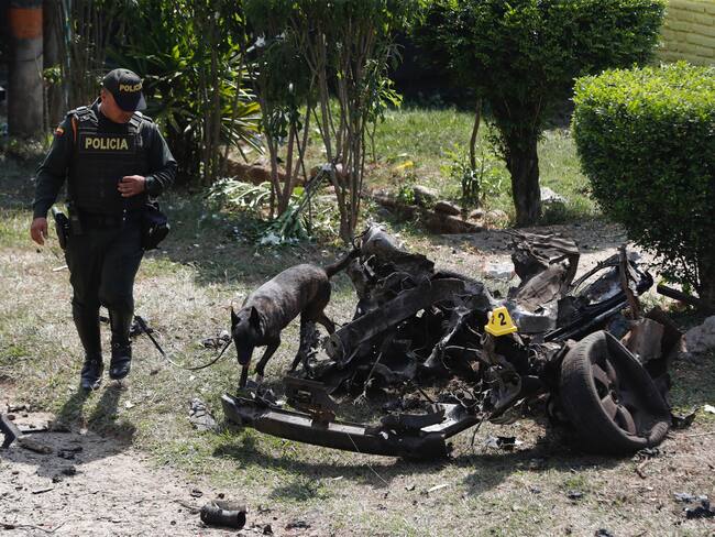AME1786. JAMUNDI (COLOMBIA), 22/09/2023.- Un policía con un perro antiexplosivos inspeccionan los restos de un carro bomba, activado contra una subestación de policía hoy, en el corregimiento Potrerito, del municipio de Jamundí, Valle del Cauca (Colombia). Al menos cinco personas resultaron heridas este viernes en una zona rural del departamento del Valle del Cauca después de la explosión de un carro bomba en cercanías de una estación policial de la localidad de Jamundí, informó la Policía. EFE/Ernesto Guzmán