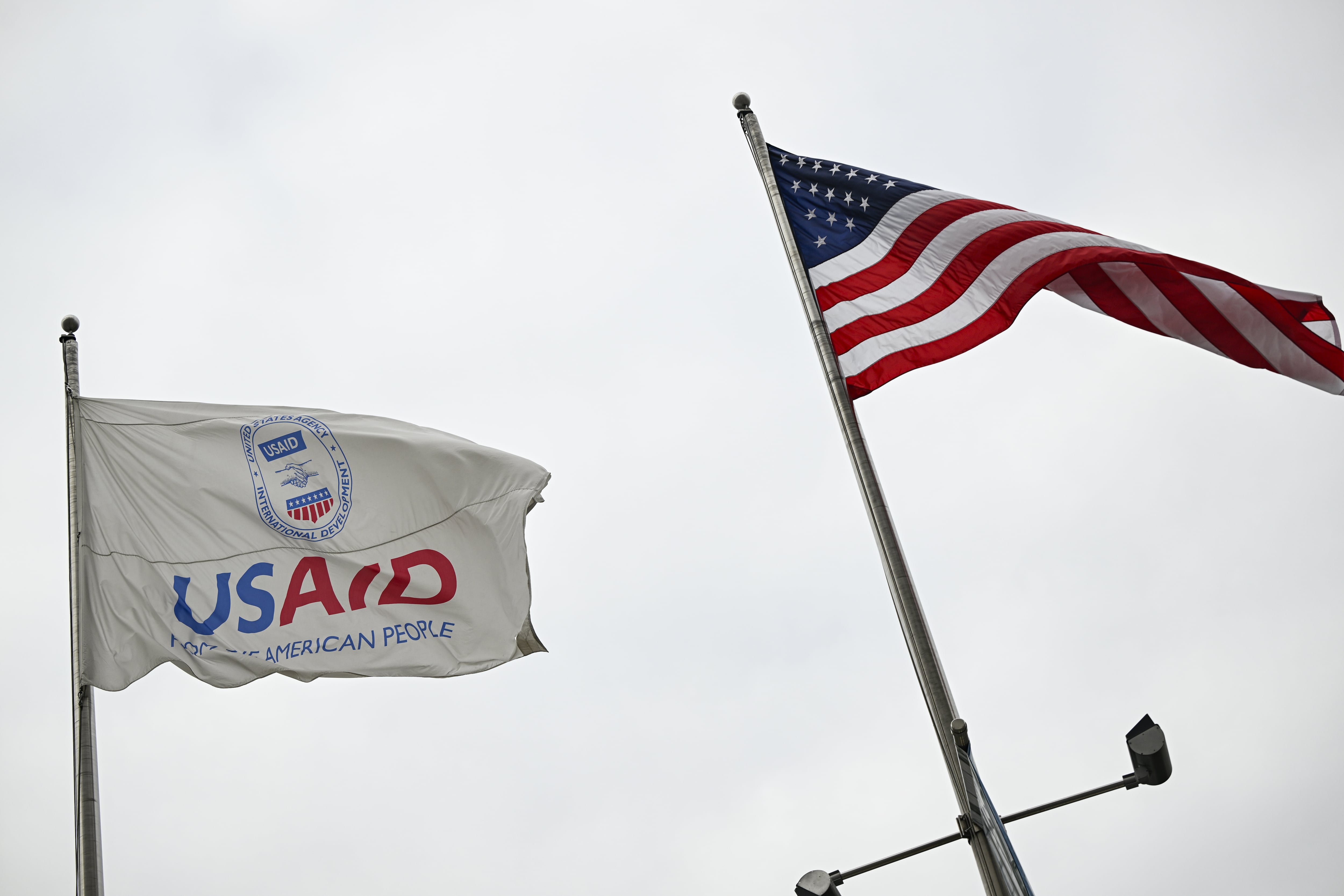WASHINGTON DC, UNITED STATES - FEBRUARY 03: The USAID and U.S. flags wave against a cloudy sky at U.S. Agency for International Development (USAID) headquarters in Washington D.C., United States on February 03, 2025. Staff across the US Agency for International Development (USAID) were abruptly informed Monday to stay out of their headquarters as tech billionaire Elon Musk said President Donald Trump has 'agreed' to shutter the agency. An email went out to all employees just after midnight informing them that 'at the direction of Agency leadership' their downtown Washington, DC headquarters 'will be closed to Agency personnel on Monday, February 3, 2025.' (Photo by Celal Gunes/Anadolu via Getty Images)