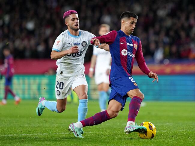 BARCELONA, SPAIN - DECEMBER 10: Joao Cancelo of FC Barcelona on the ball whilst under pressure from Yan Couto of Girona FC during the LaLiga EA Sports match between FC Barcelona and Girona FC at Estadi Olimpic Lluis Companys on December 10, 2023 in Barcelona, Spain. (Photo by Alex Caparros/Getty Images)